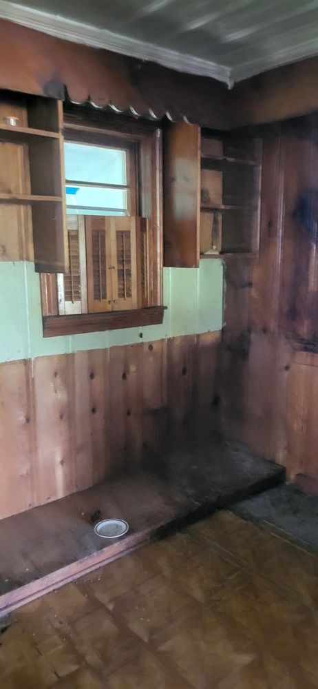 Room interior with wood paneling, built-in shelving, and a window.