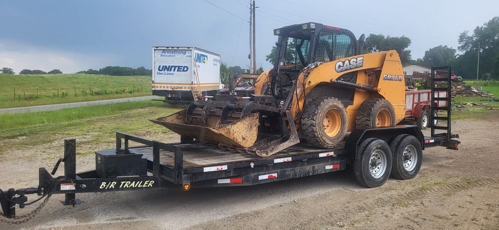 A CASE skid steer loader on a trailer in a rural setting.