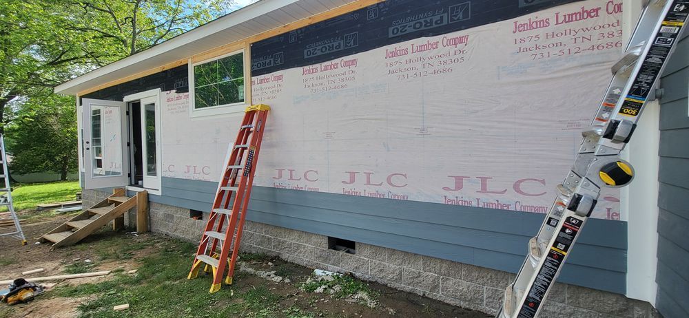 House under construction; siding installation, ladders, doors and windows.