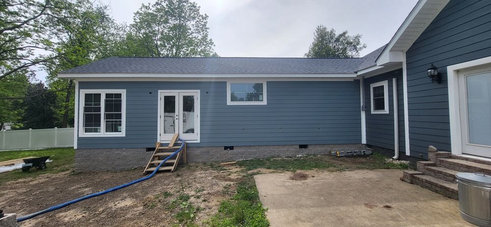 Blue-sided house with white trim, windows, and French doors. Wooden steps lead up to the doors.