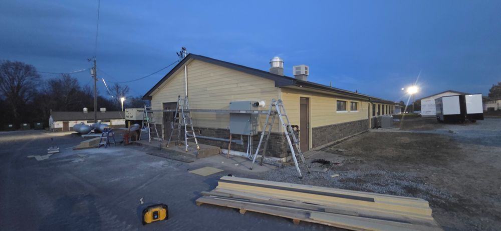 Building under construction with scaffolding, tools, and materials. Evening with a dark blue sky.