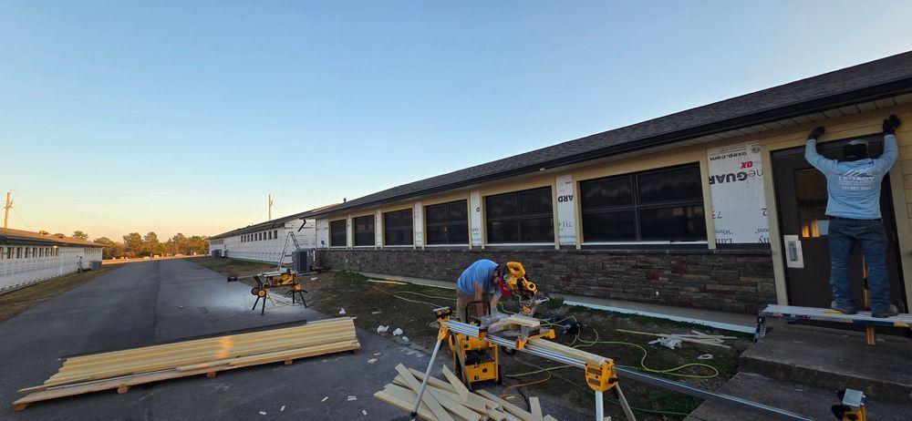 Construction workers working on a building exterior, cutting wood and installing siding.