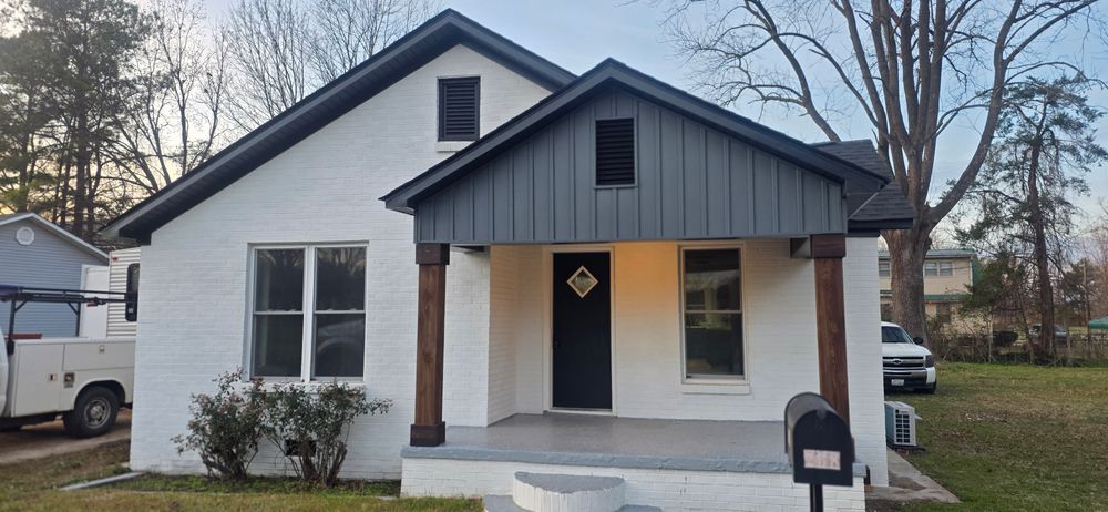 White house with a gray porch roof, dark door, and brown pillars. A truck and lawn are in front.