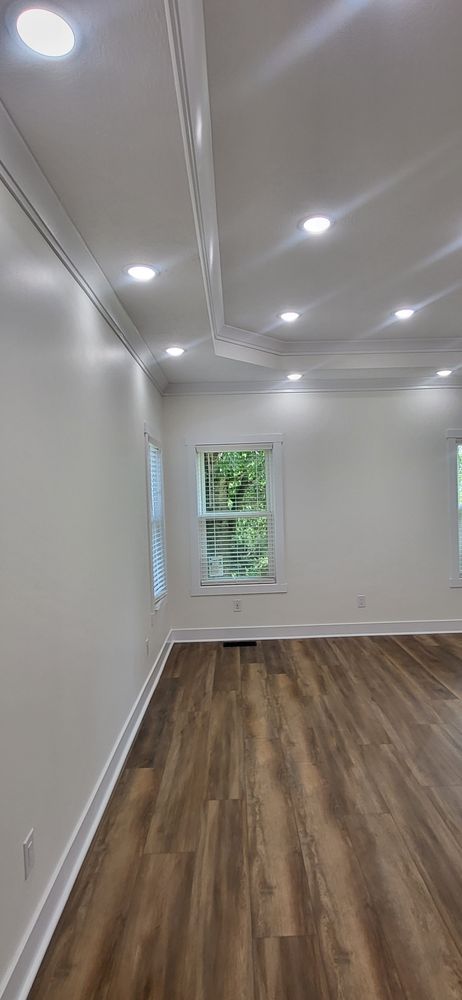 Interior room with wood-look floor, white walls, crown molding, and recessed lighting; a window with green view.
