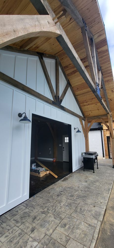 White building exterior with dark trim and wooden beams. Gray stamped concrete walkway.