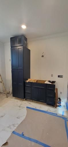 Dark blue cabinets installed in a room under construction. White walls, protective coverings on floor.