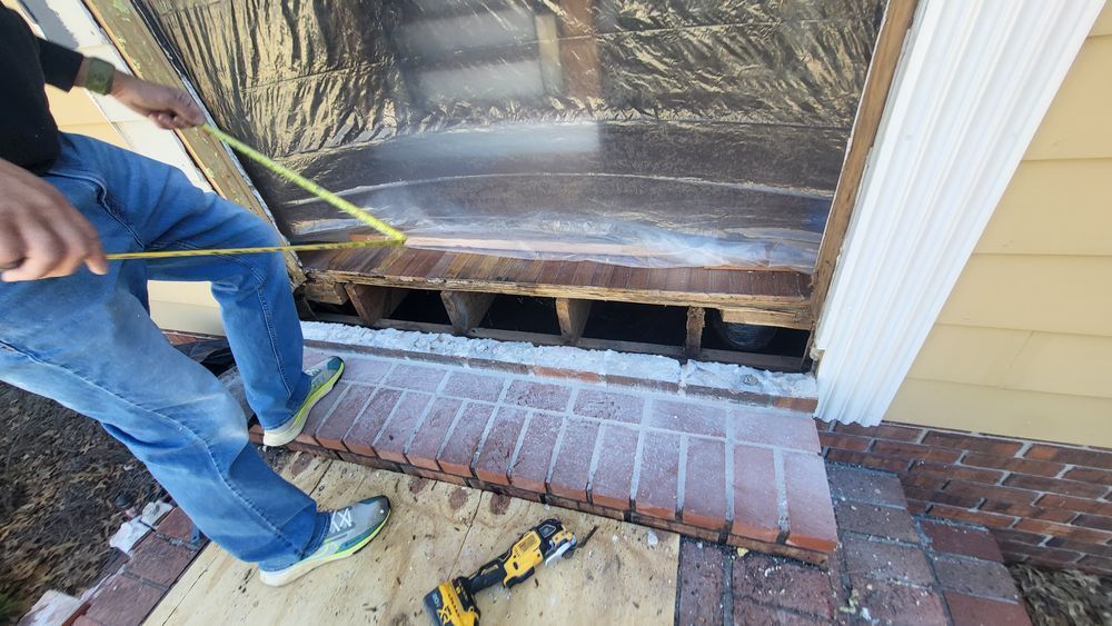 Person measuring a window frame with a yellow tape measure during a home repair.