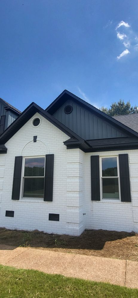 White house with black trim and shutters against a blue sky.