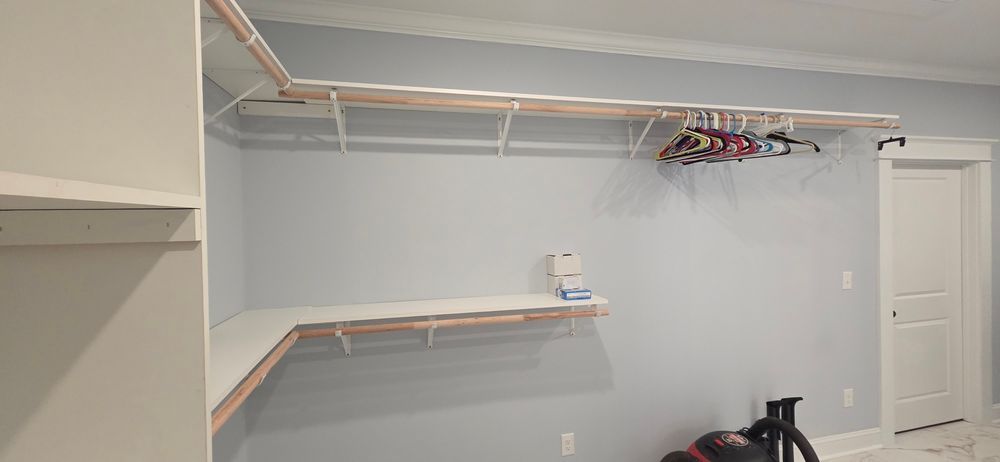 Empty walk-in closet with shelves and hanging rods. Light blue walls, white trim and shelves.