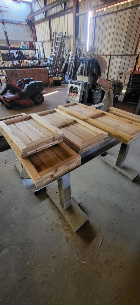 Wooden panels resting on a table in a workshop, with other tools and equipment visible in the background.