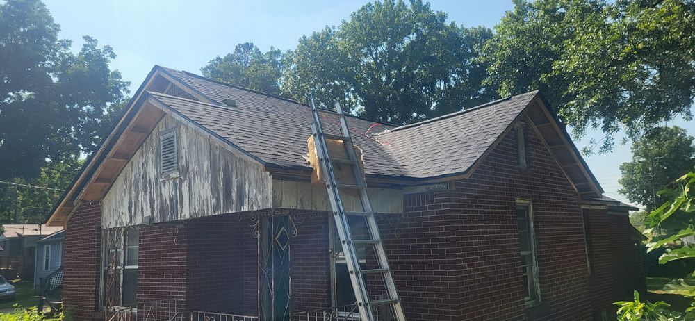 A house with a newly shingled roof and a ladder propped against it, trees in the background.