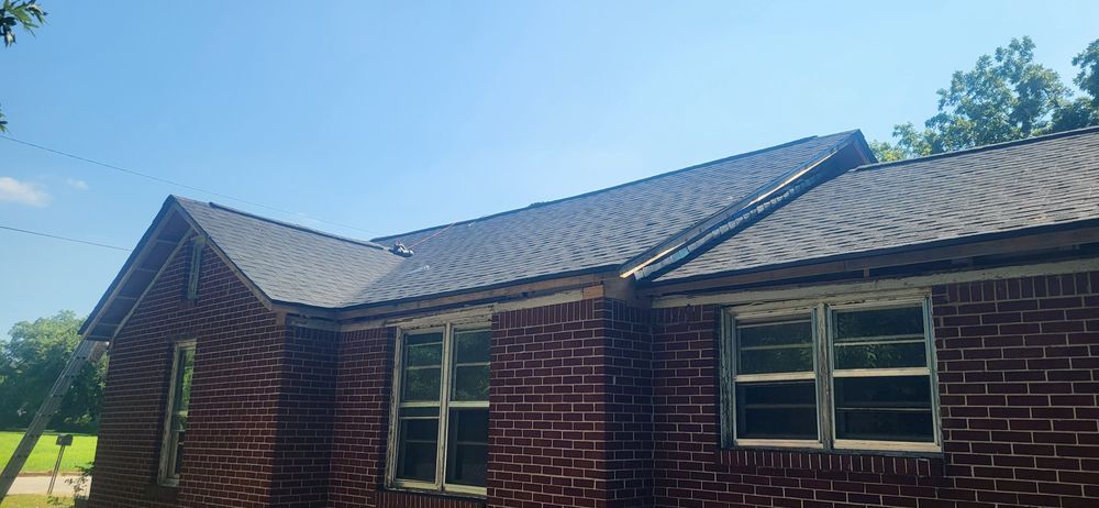 Brick house with a dark gray roof against a blue sky.