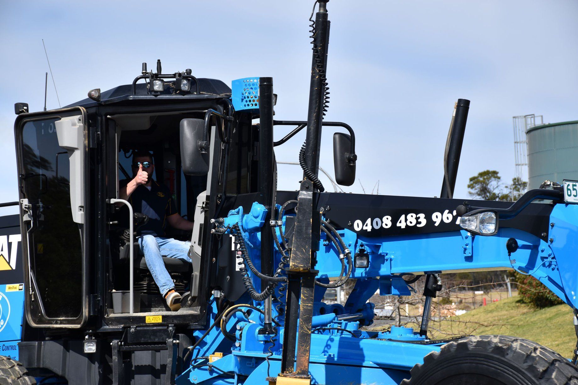 Man Driving Blue Grader — Marulan, NSW — Coopers Earthmoving Pty Ltd
