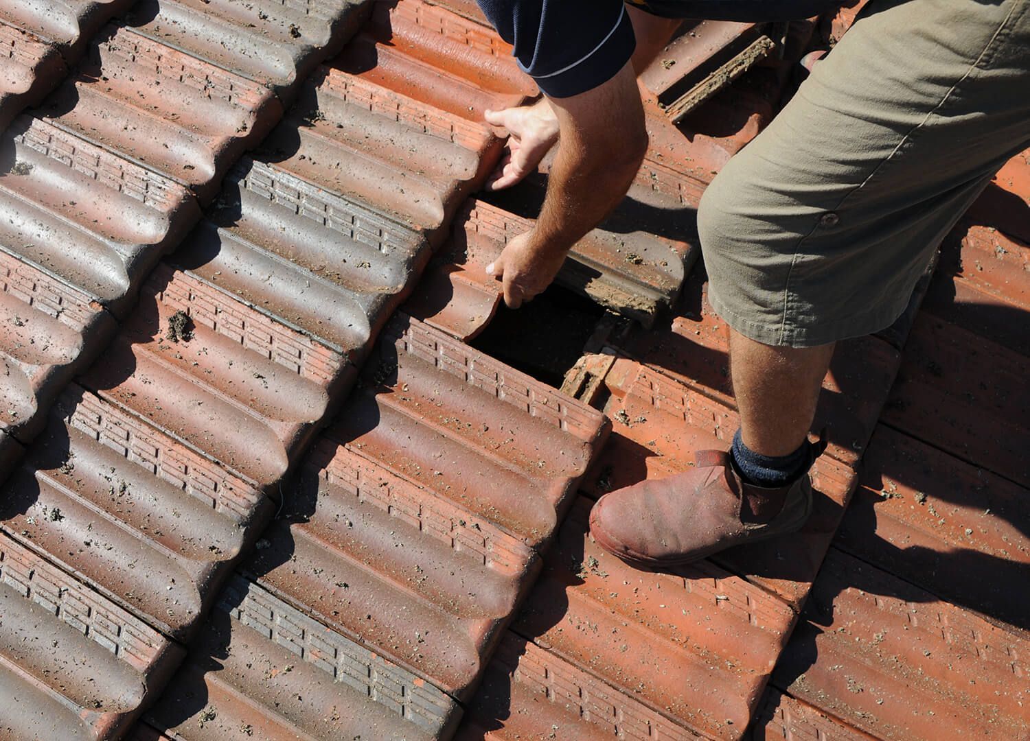 Roofers diligently removing old material from a house, getting it ready for storm damage repair.