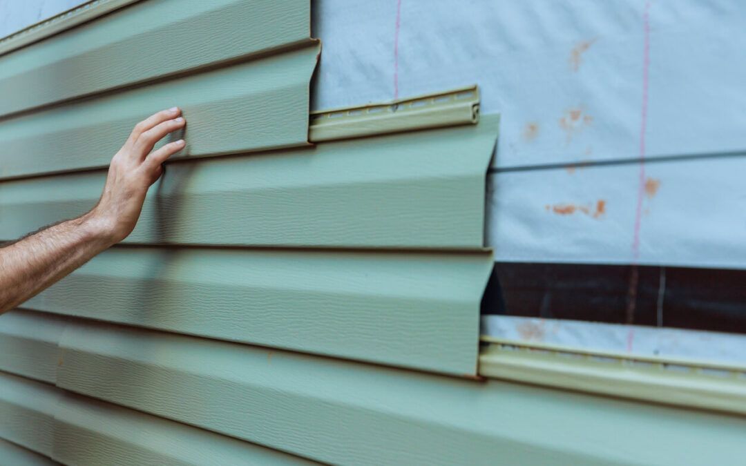 A group of workers installing siding on a house.