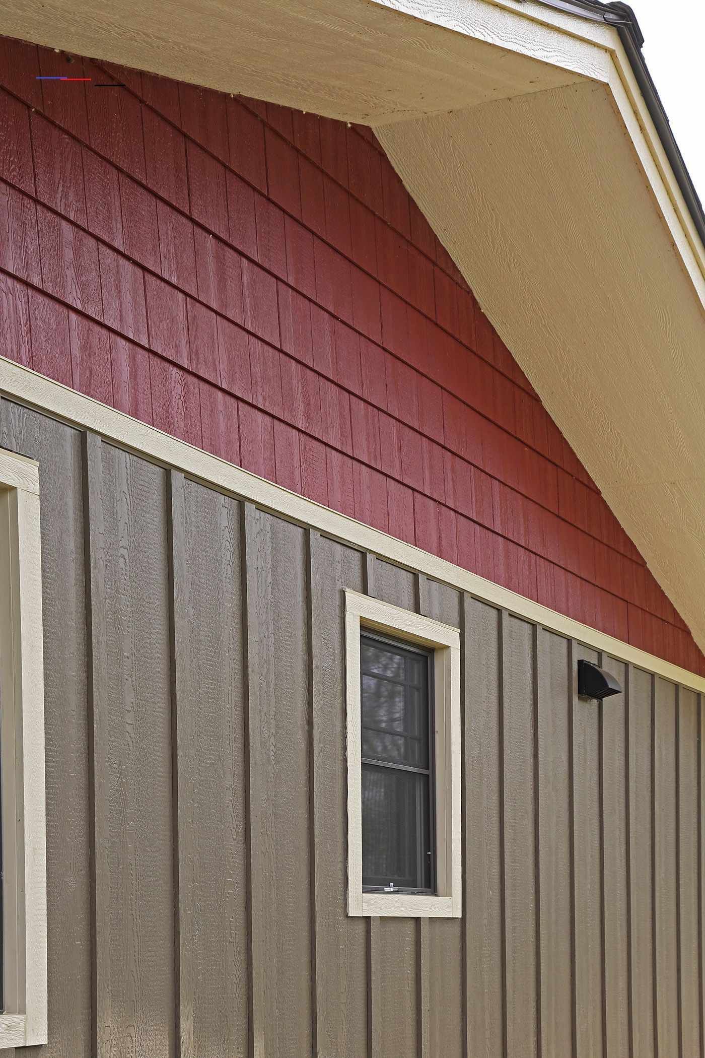 A worker wearing gloves is installing siding on the exterior of a house.