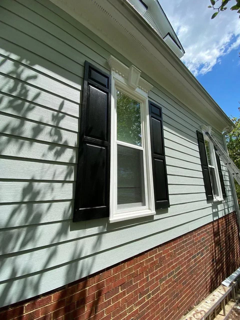 A man carefully installing hinges on a window frame with focused precision.