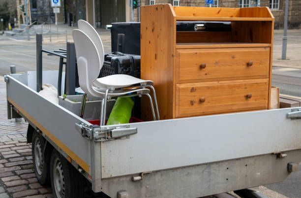 An image of a trailer filled with used chairs, dressers, tables, and cabinets.