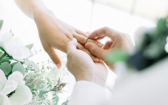 wedding flowers, man placing ring on woman's finger