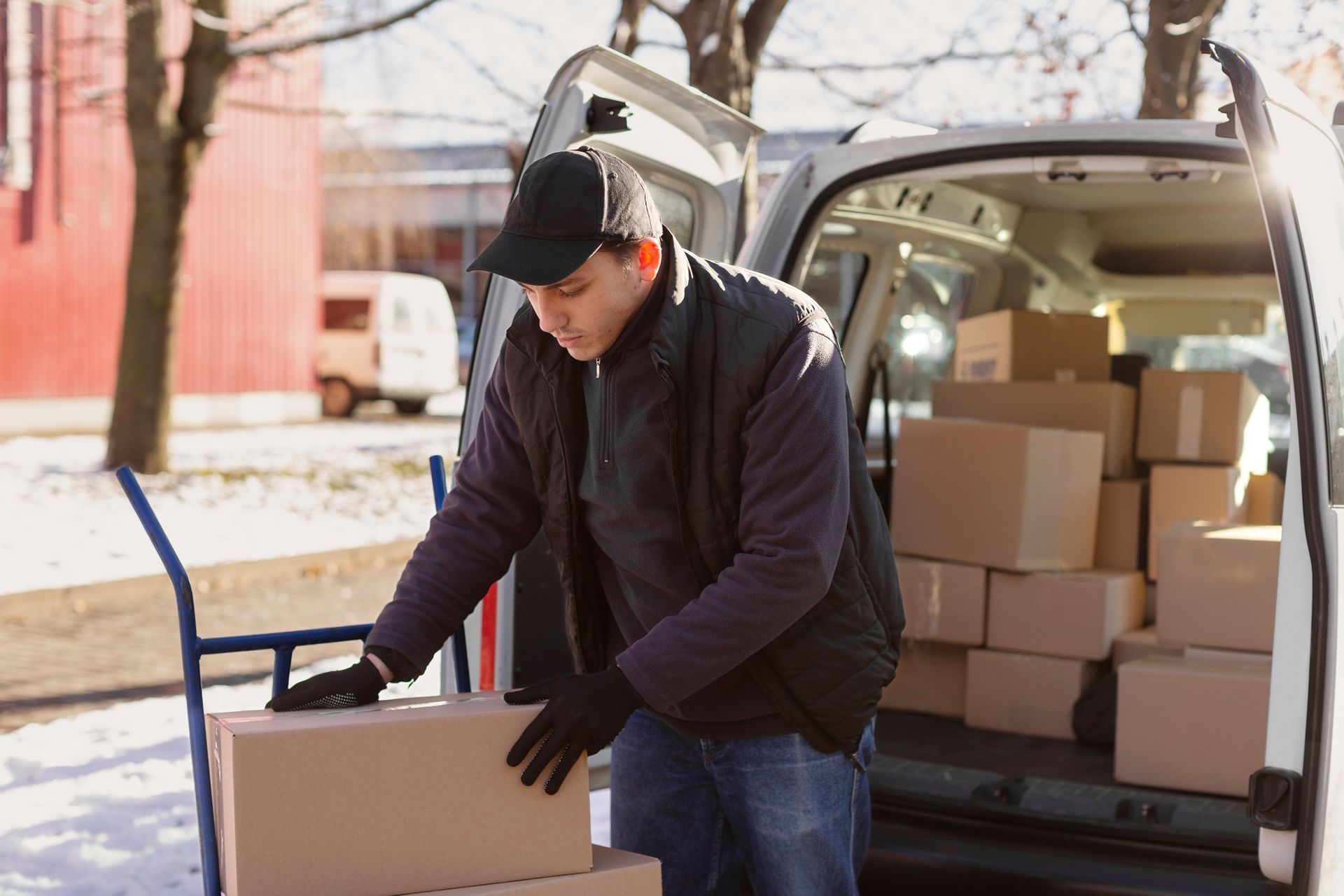 A delivery man is loading boxes into the back of a van.