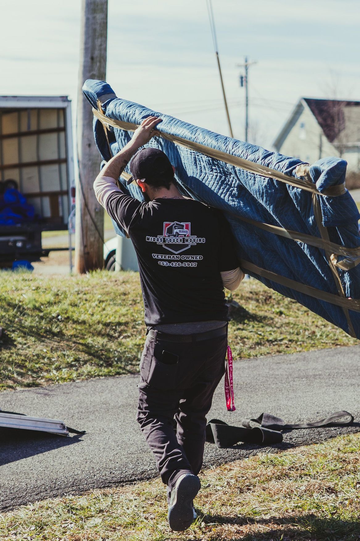 Two men are carrying a couch in a living room.