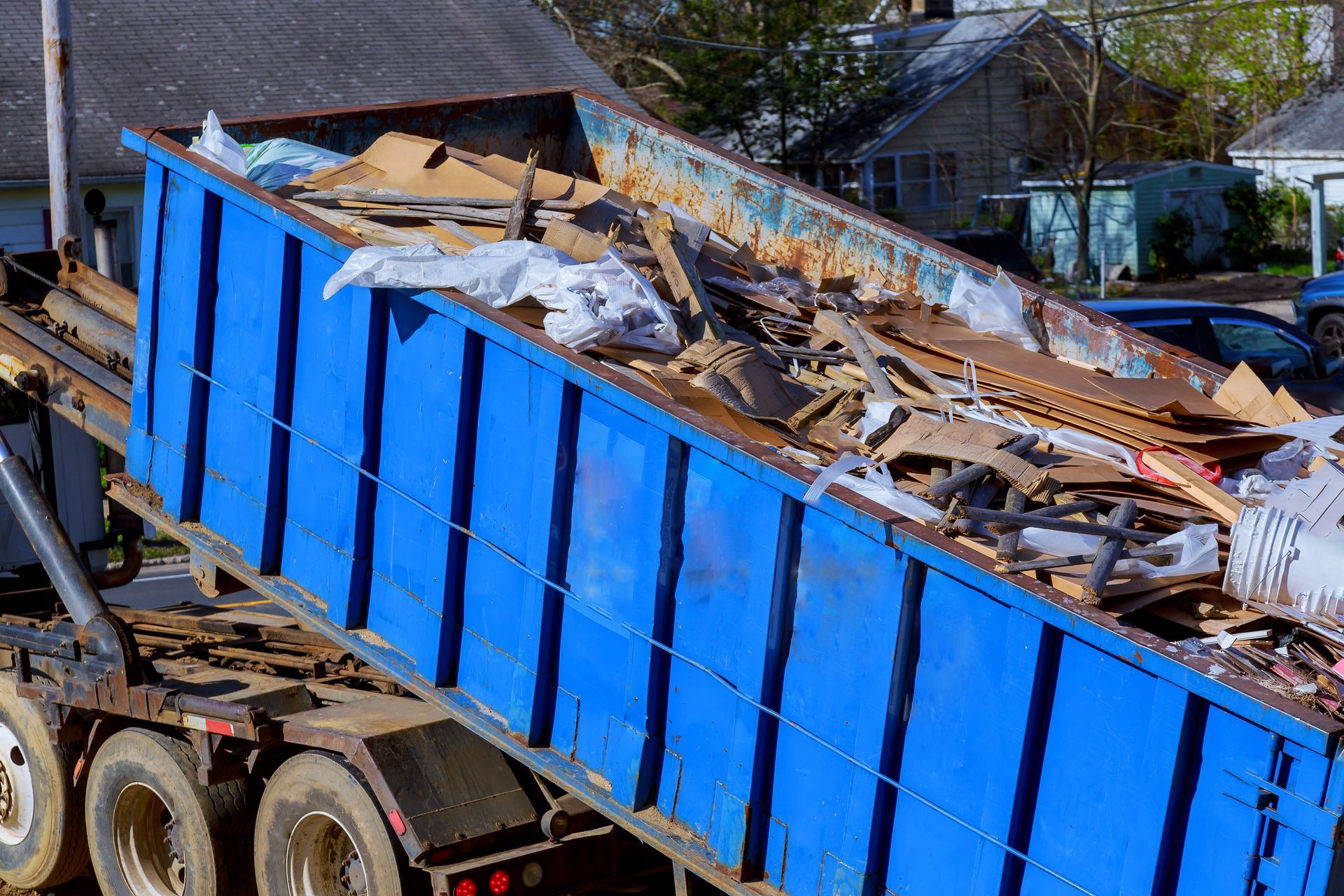 A blue dumpster truck is filled with wood.