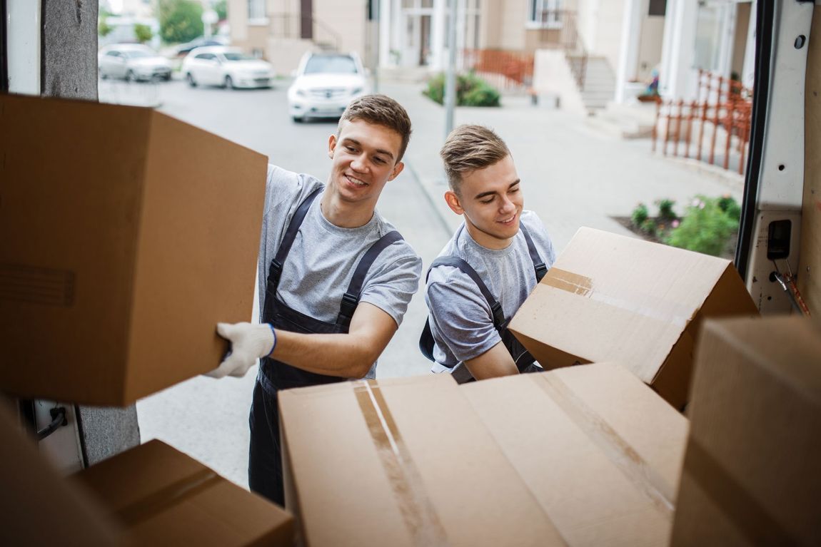 Two men are carrying boxes out of a truck.