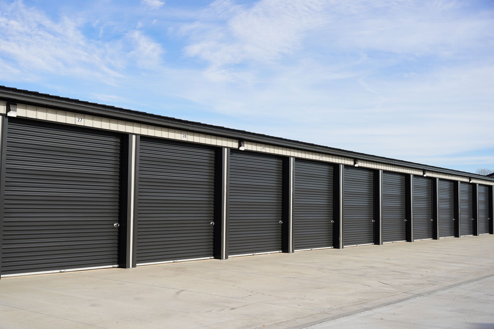 A row of black garage doors with a blue sky in the background.