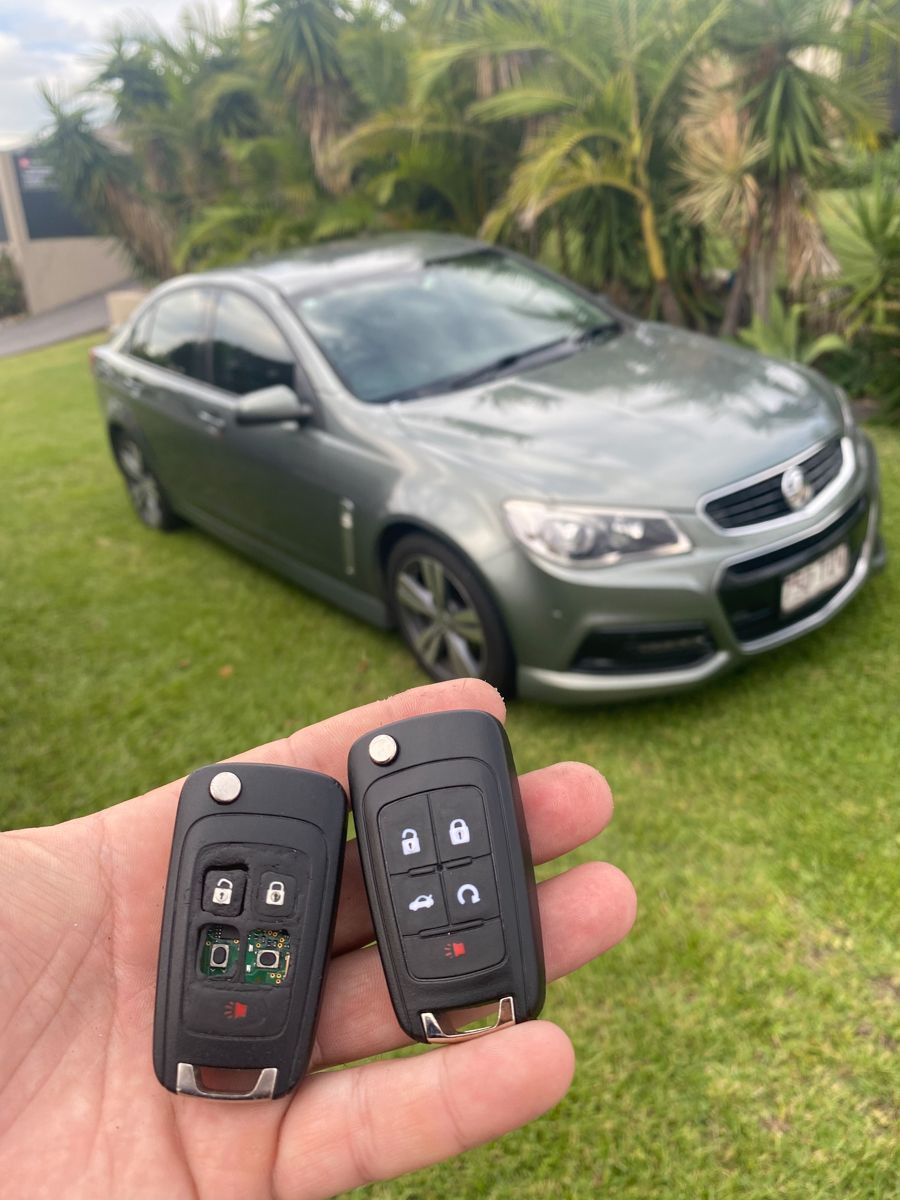 A person is holding a car key in front of a blue car.