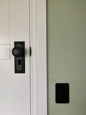 A white door with a black door knob and a black light switch.