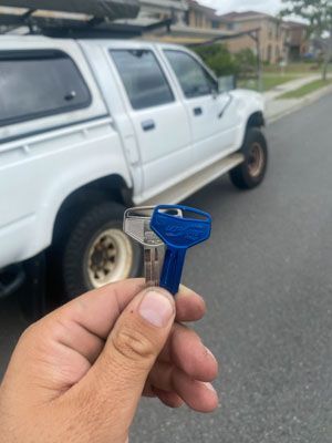 A person is holding a blue key in front of a white truck.