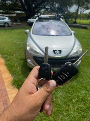 A person is holding a car key in front of a car.