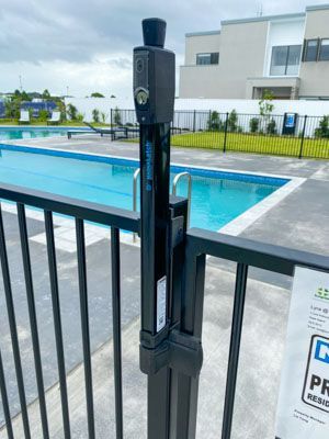 A fence with a lock on it is next to a swimming pool.