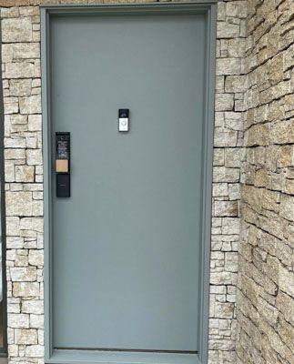A gray door is sitting on a stone wall.