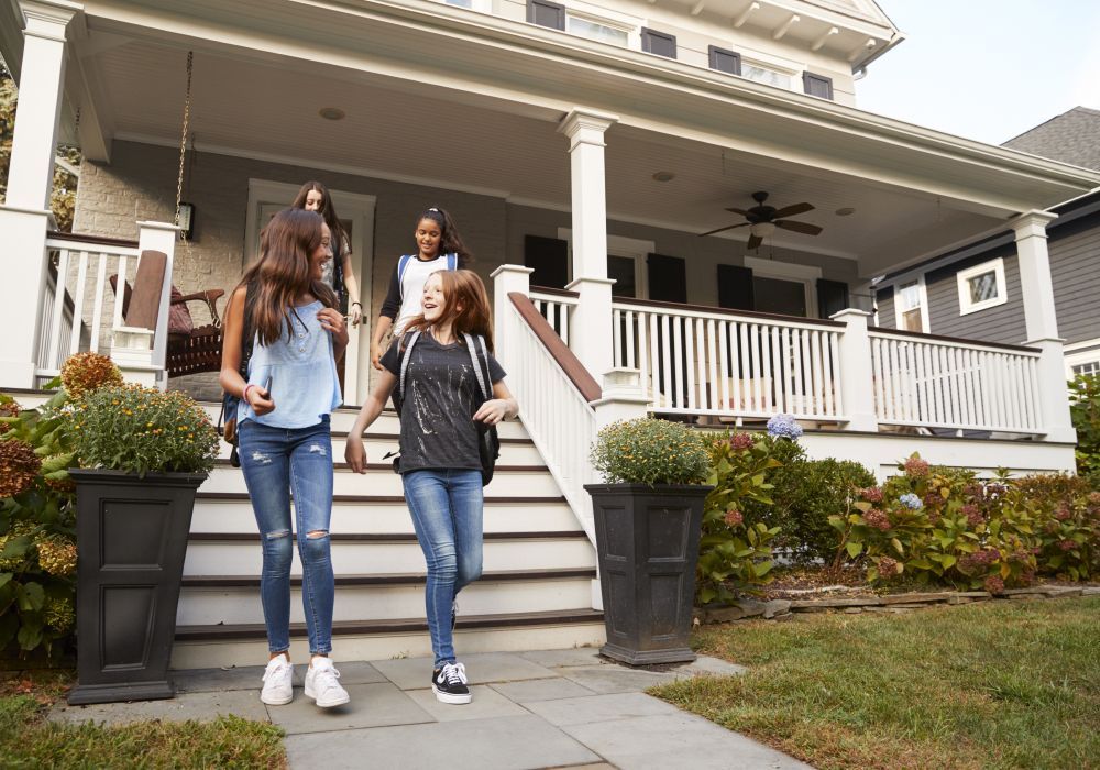 A group of young girls are walking down the stairs of a house.