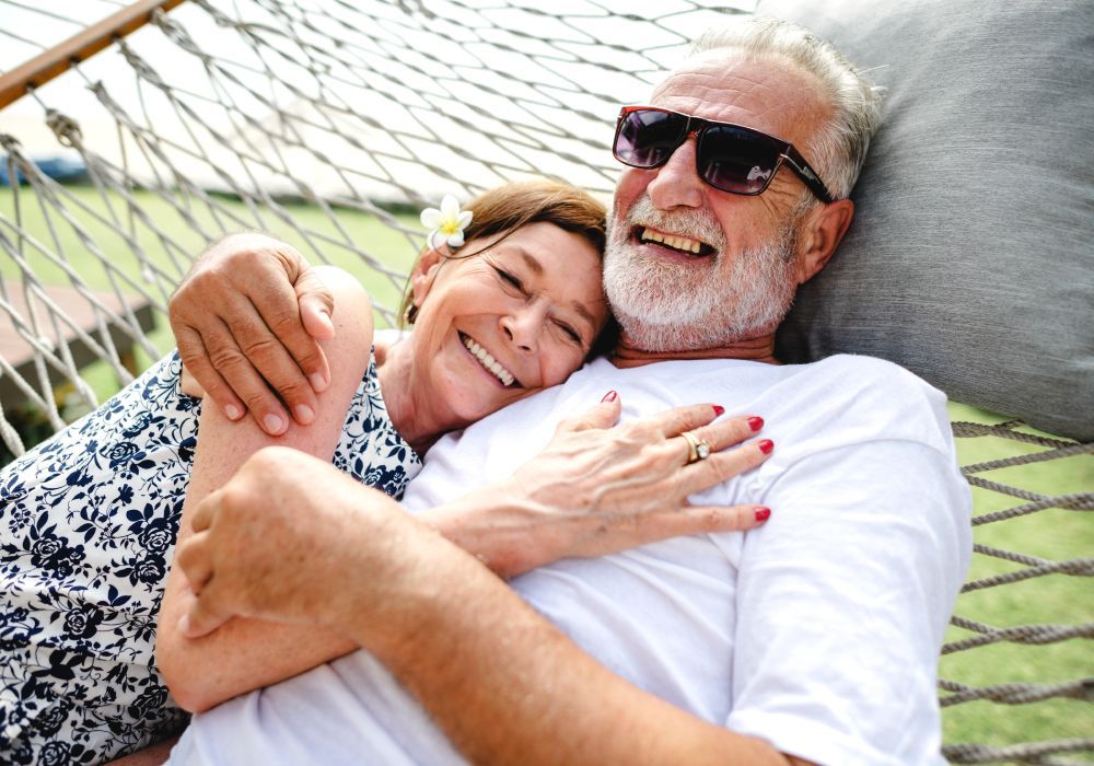 A man and a woman are laying in a hammock.