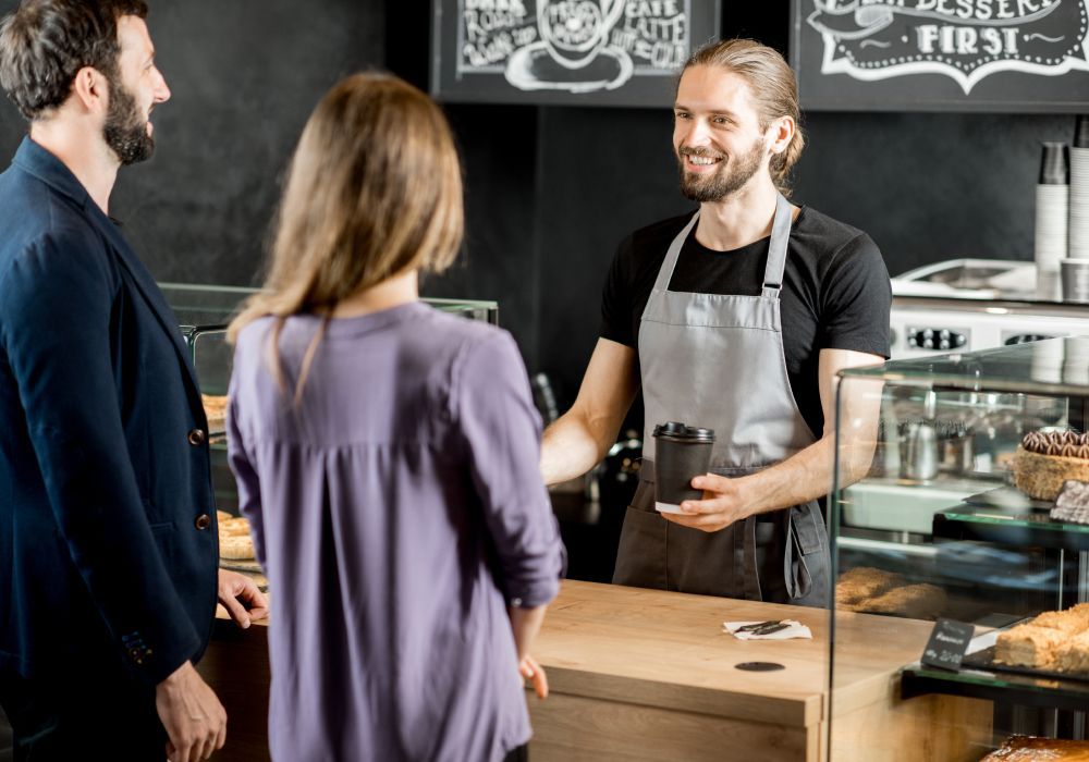 A man is shaking hands with a woman in a coffee shop.