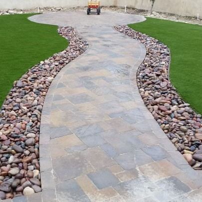 A stone walkway leading to a lawn with rocks and grass.