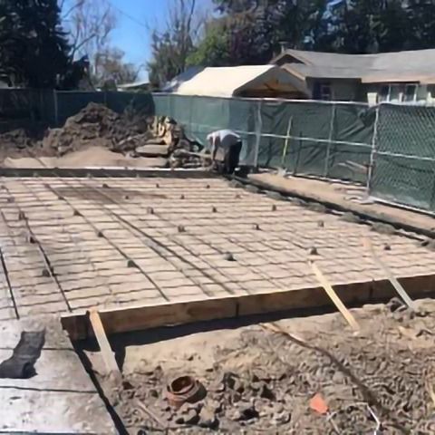 A man is working on a concrete base of a house.