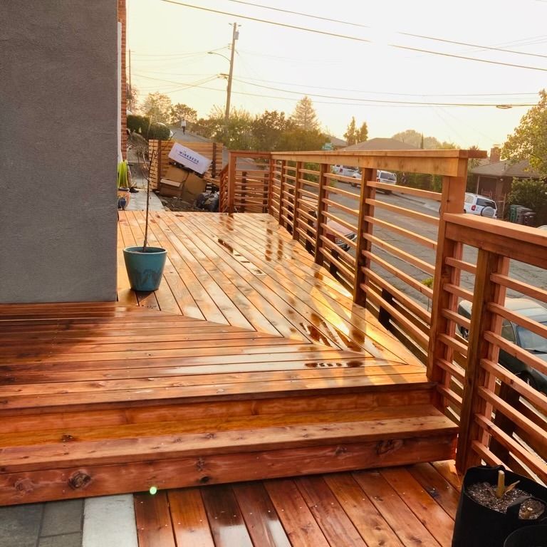 A wooden deck with a railing and a potted plant on it