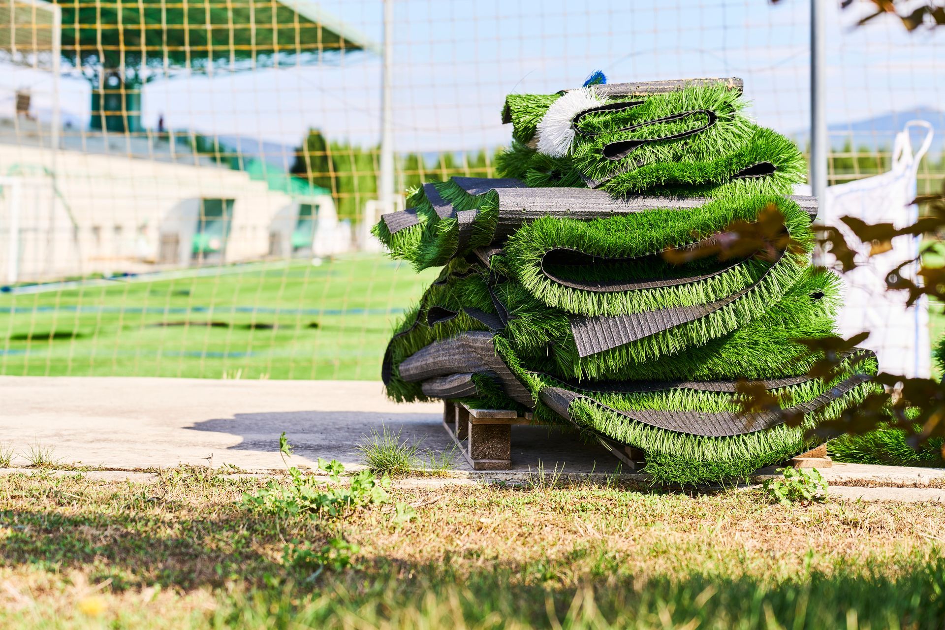A pile of artificial grass is sitting on top of a pallet on a soccer field.