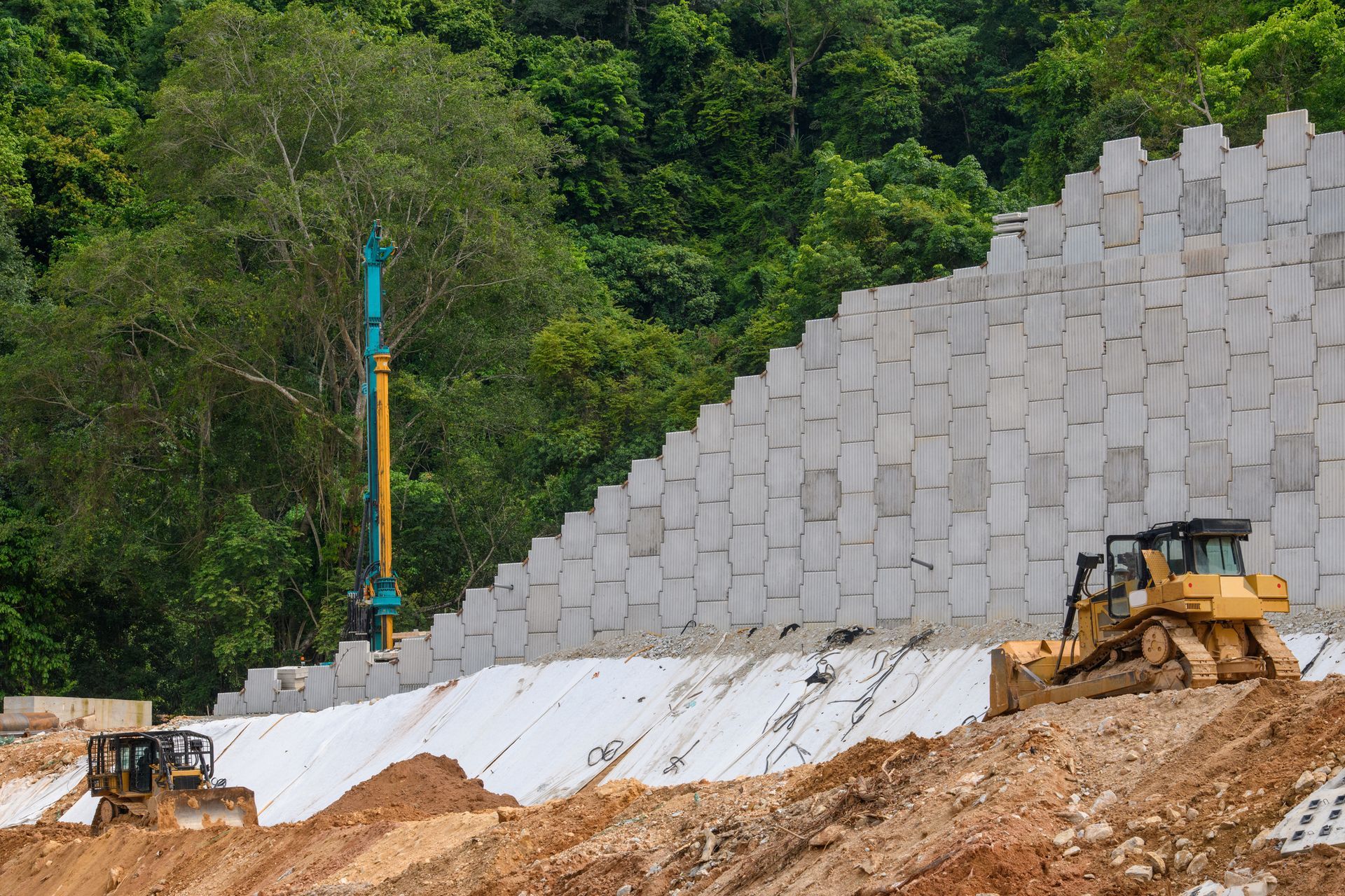 A bulldozer and a crane are working on a construction site.