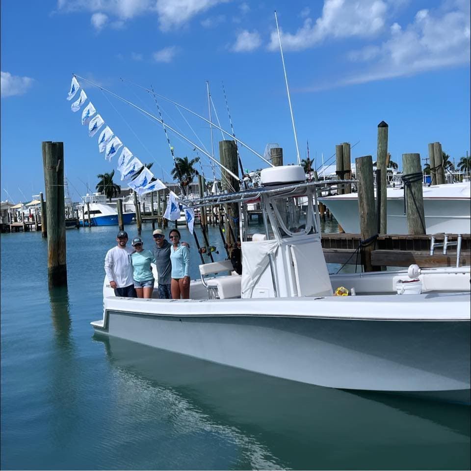 A group of people are posing for a picture in front of a boat with a banner that says ' florida ' on it