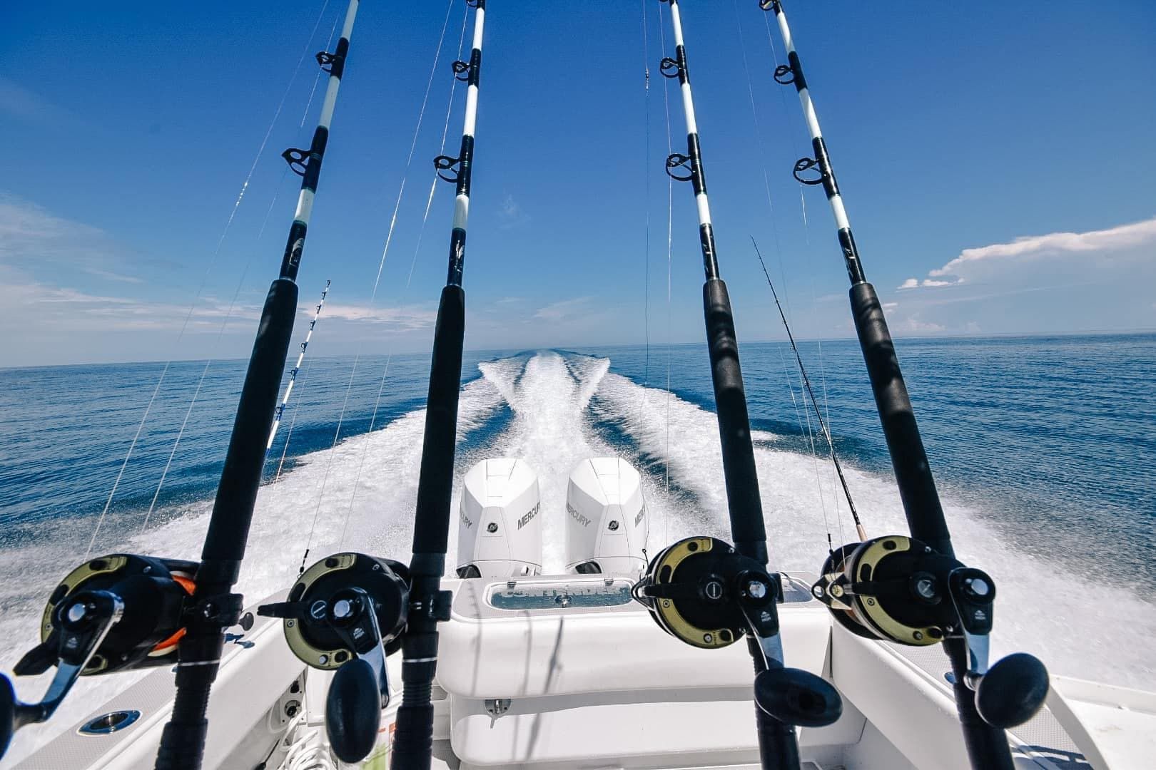 Four fishing rods are on the back of a boat in the ocean
