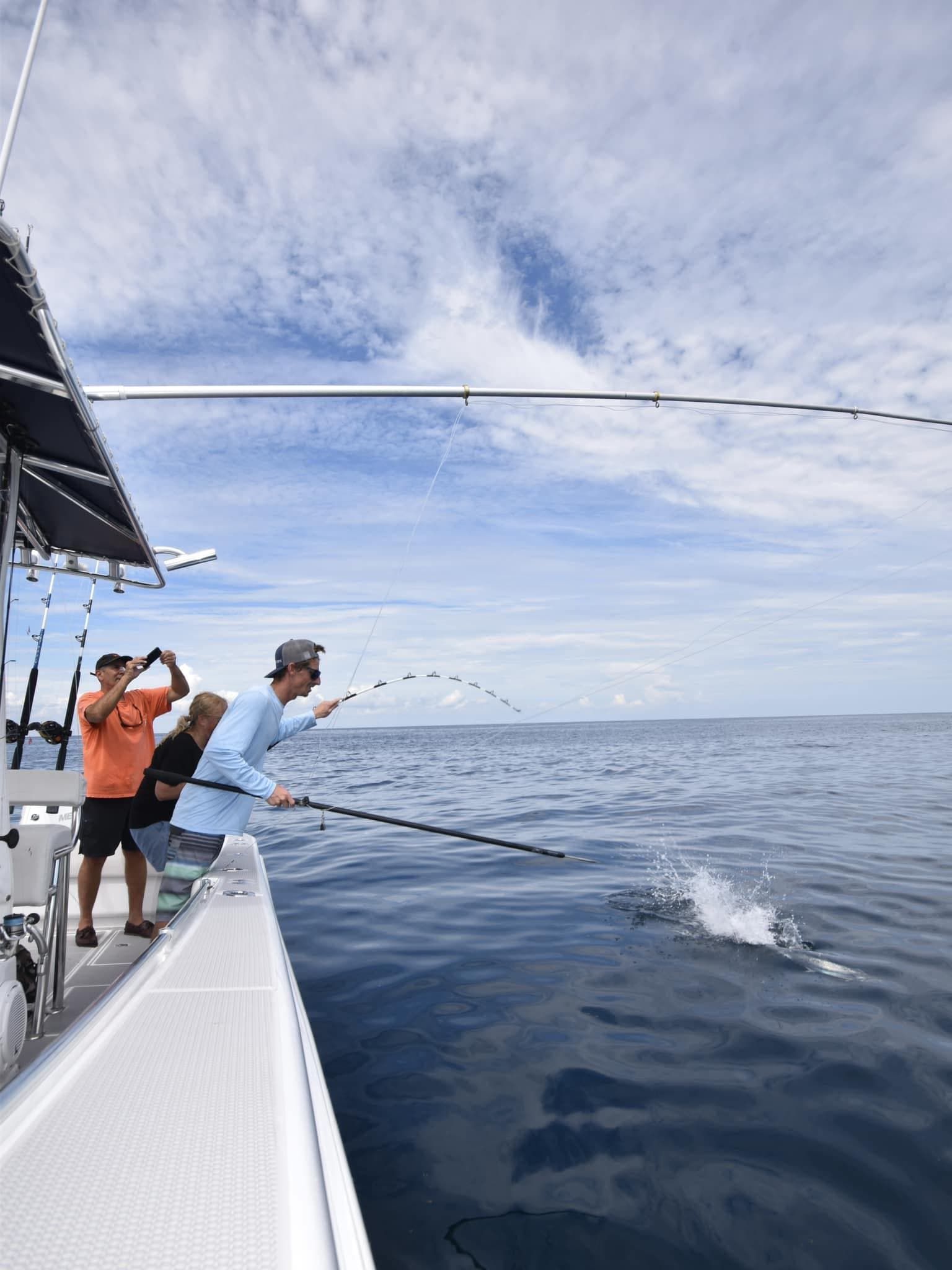 A group of people are fishing on a boat in the ocean.