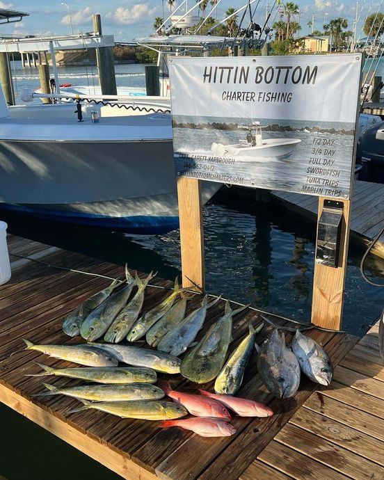 A bunch of fish are sitting on a wooden dock next to a boat.
