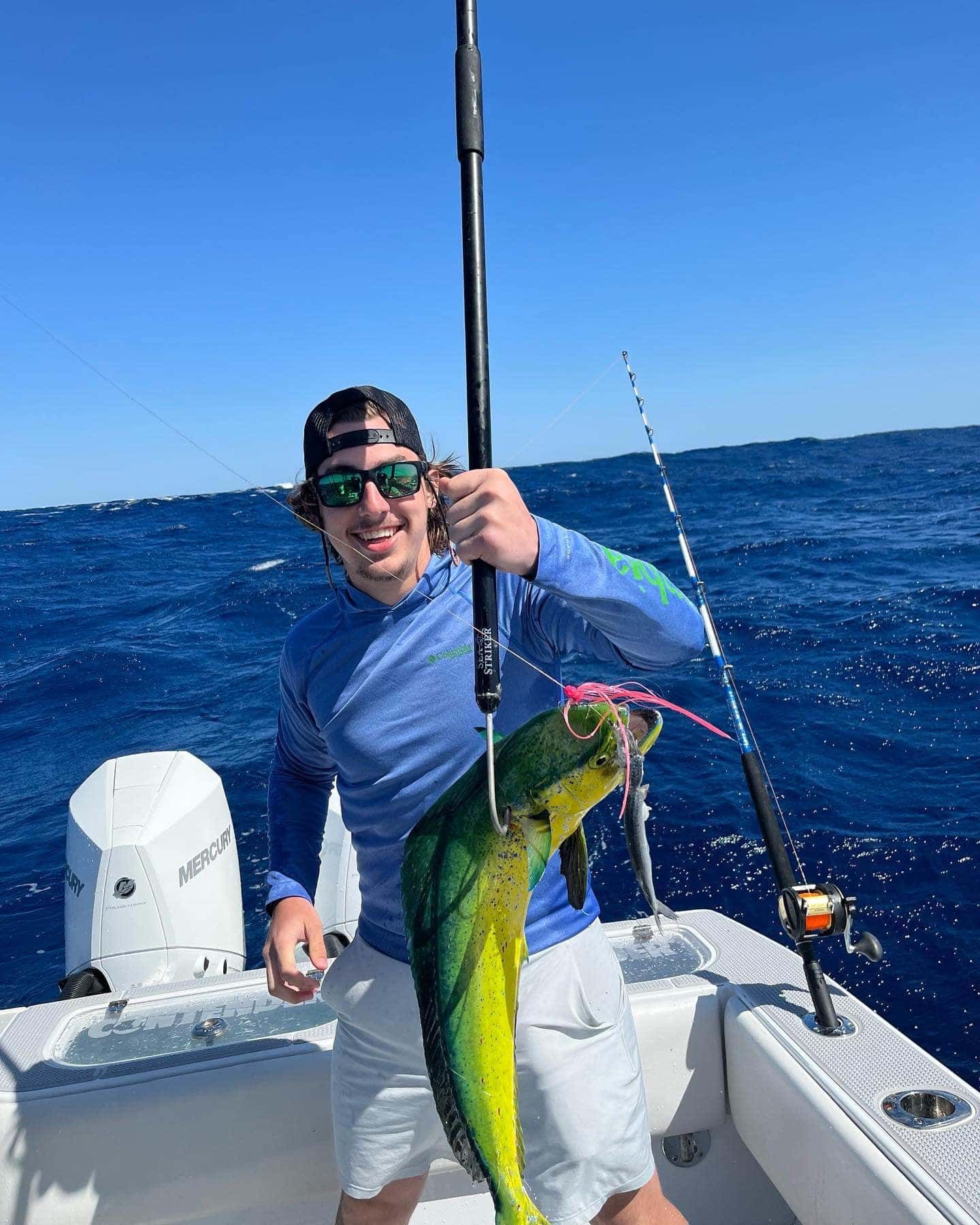 A man is holding a fish on a boat in the ocean.