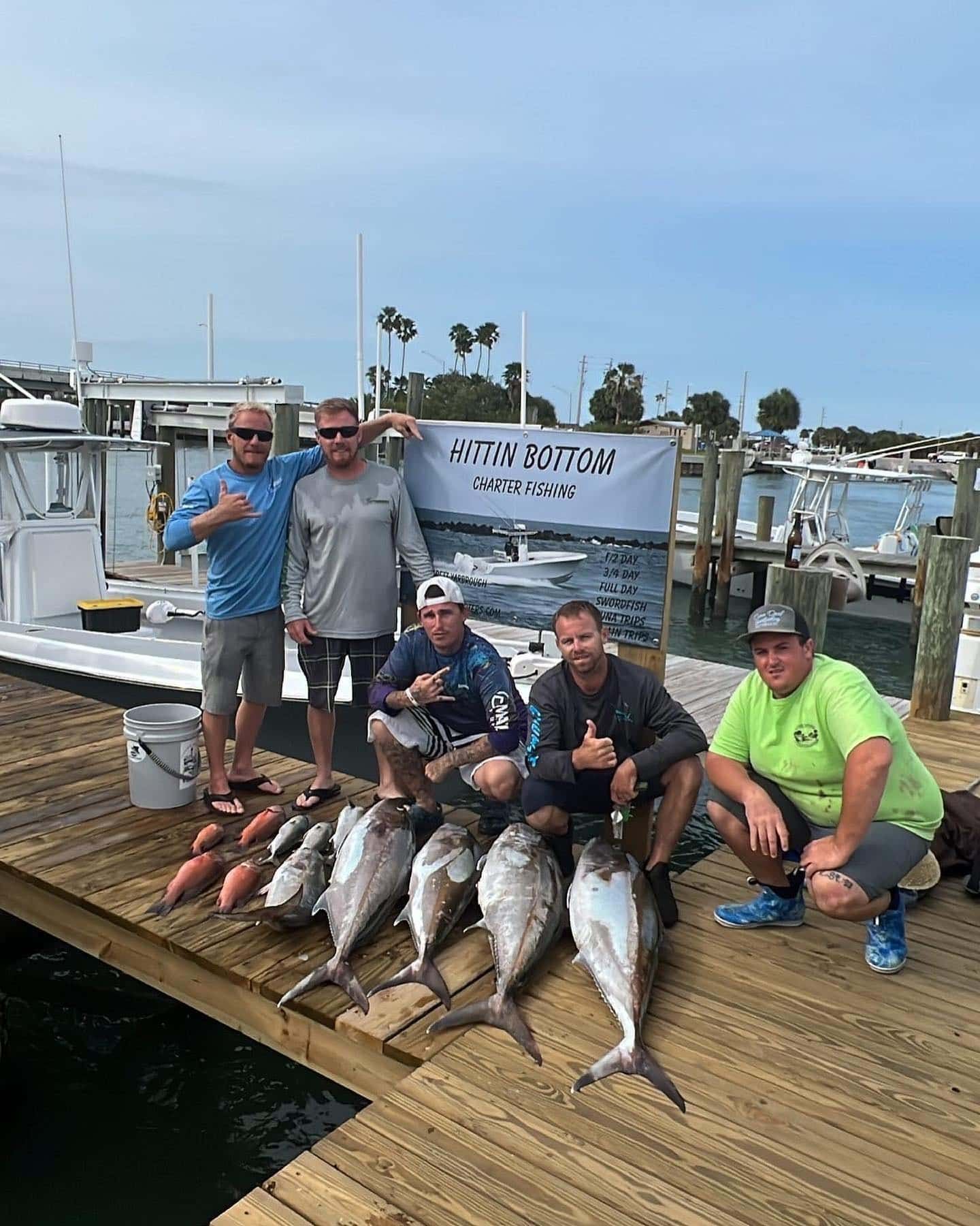A group of men are posing for a picture with their catch of fish on a dock.