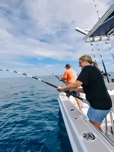 A man and a woman are fishing on a boat in the ocean.