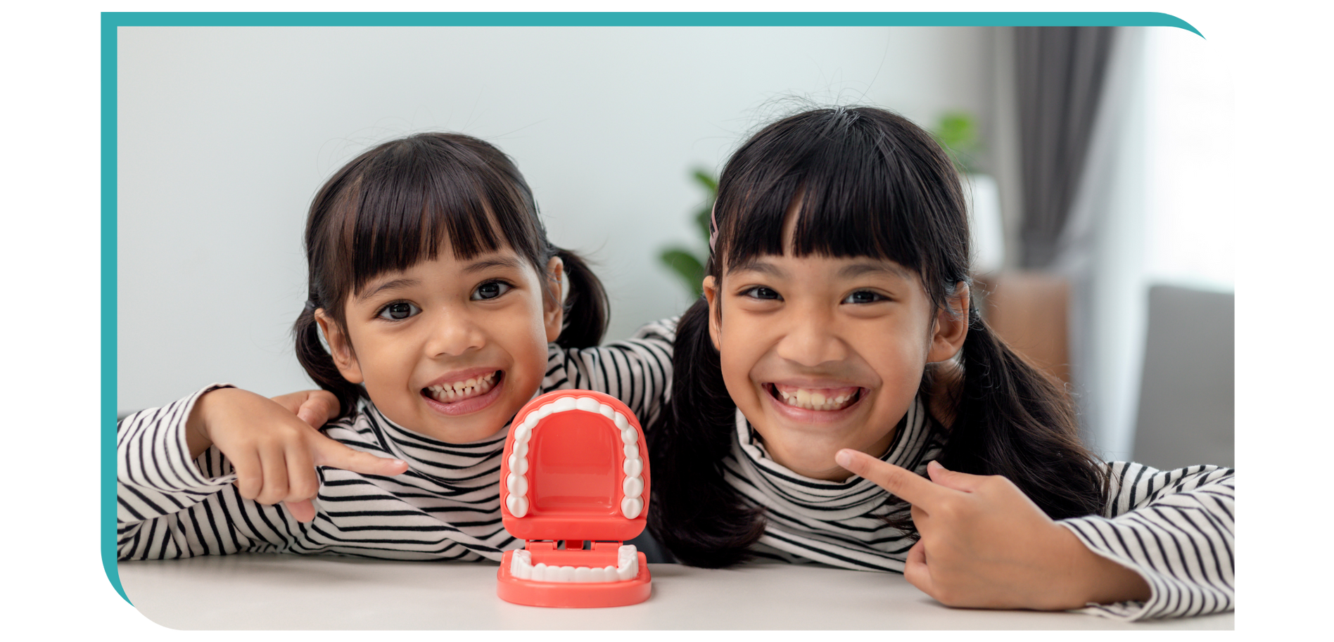 two little girls pointing at a model of teeth